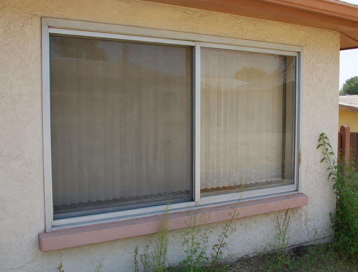 Dated aluminum sliding windows on an older stucco home